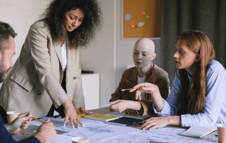 Four people sat around a board table brainstorming ideas.