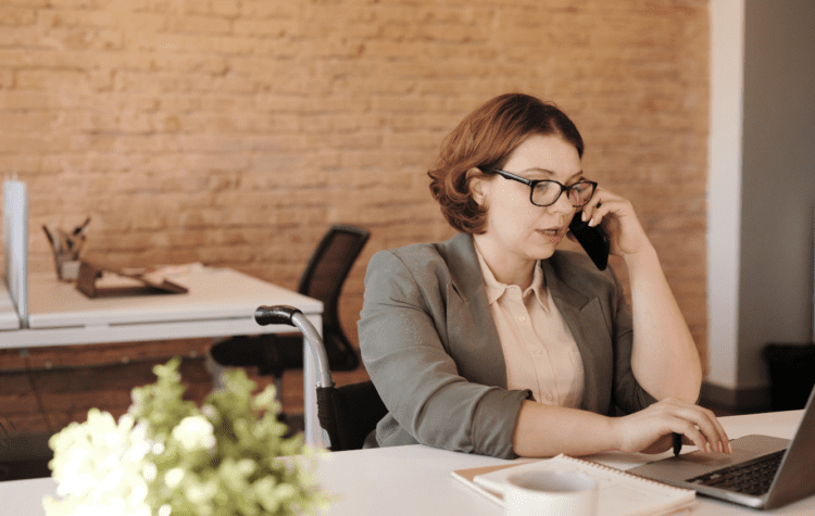 A woman at her desk on the phone discussing how much recruitment agencies charge for contractors.